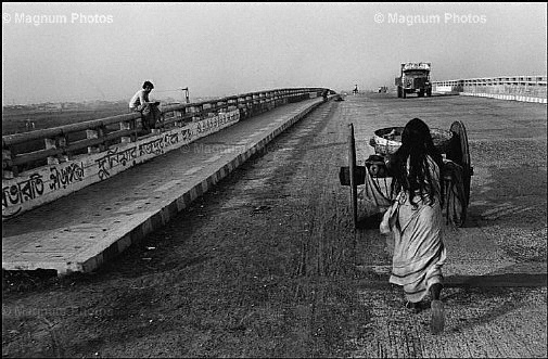 Una donna spinge il carretto lungo la strada.jpg